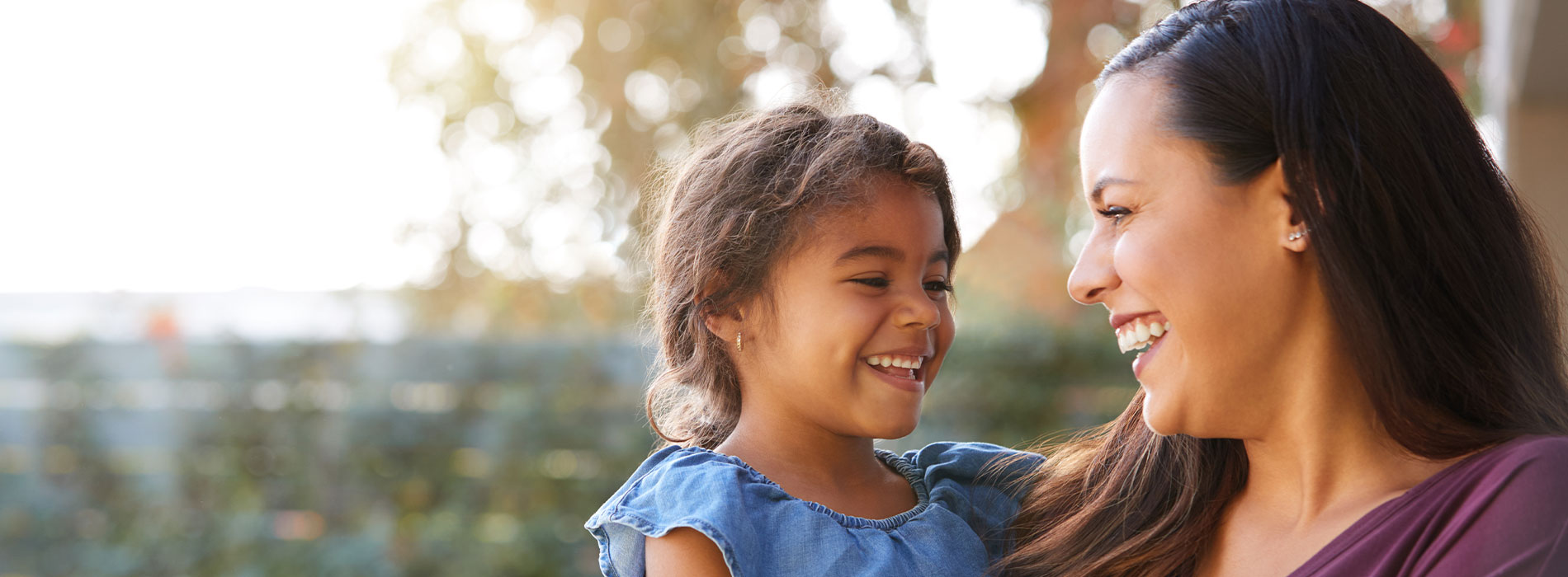 The image depicts a woman holding a young child outdoors during daylight hours.