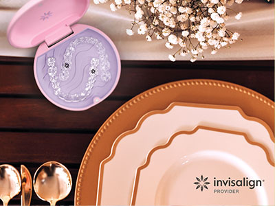 The image shows a table set with plates, bowls, and other dining ware, with a focus on a pink toothbrush box and a tray of dental care items, suggesting a theme related to oral hygiene products.