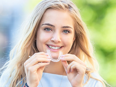 A woman holding up a toothbrush with a smile on her face.