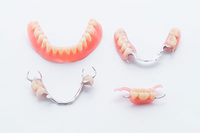 The image shows a set of dental braces with pink teeth-shaped plastic attachments placed on top of a metal wire frame, displayed against a plain background.