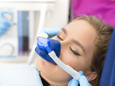 A woman receiving medical treatment with an oxygen mask and being attended to by a healthcare professional.